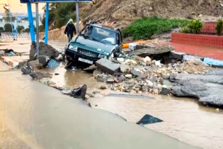 Une voiture bloquée dans les débris d'une chaussée endommagée par les inondations survenues à Safi, le 14 décembre 2025