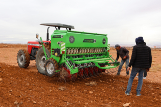 Des agricultures préparant un tracteur équipé d'un semoir mécanique sur une exploitation dans la région de l'Oriental.