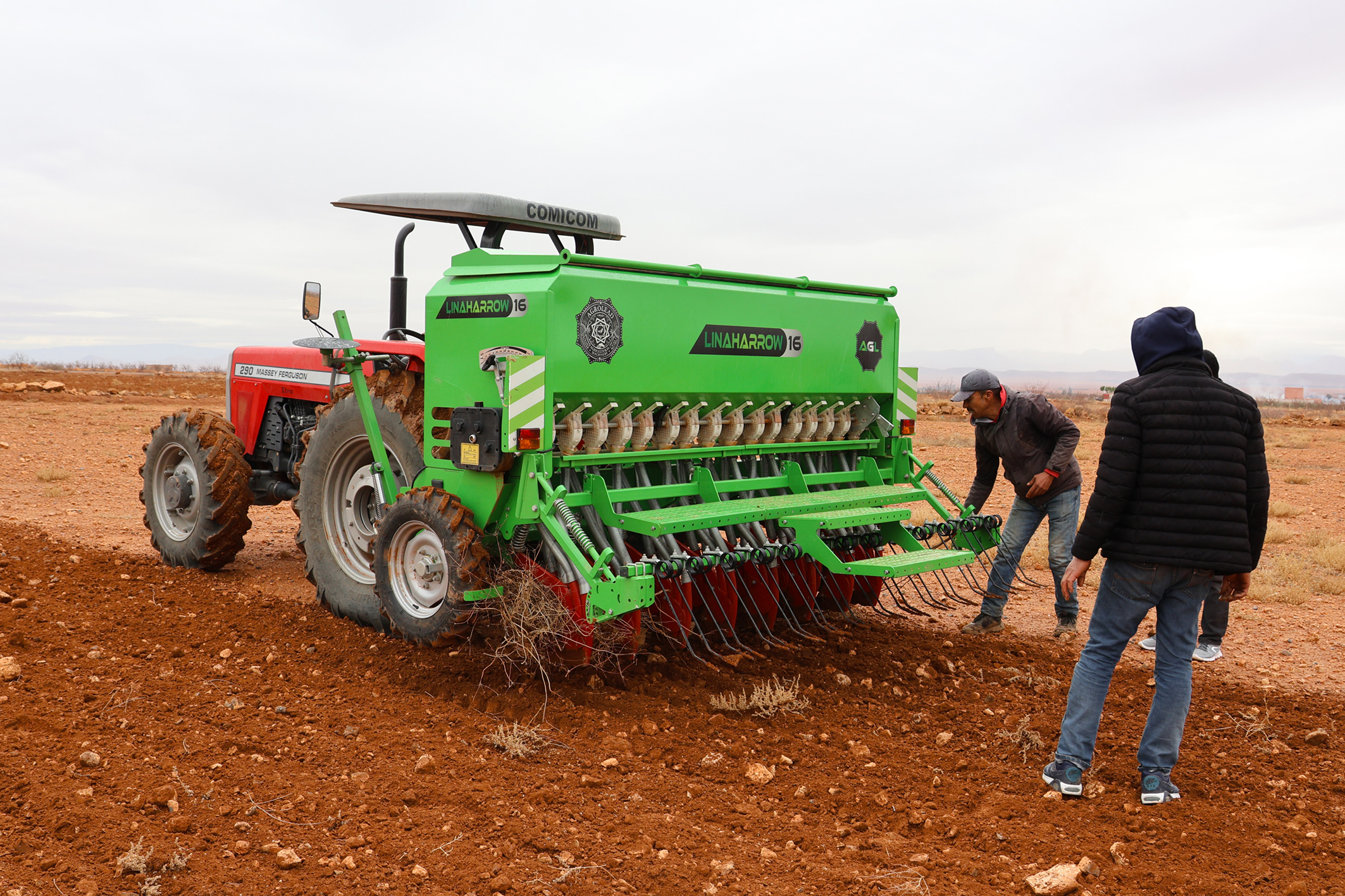 Des agricultures préparant un tracteur équipé d'un semoir mécanique sur une exploitation dans la région de l'Oriental.