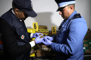 Un élément de la Sûreté nationale et un agent des douanes examinant la cargaison de chira saisie au port Tanger Med, le 19 mars 2026.