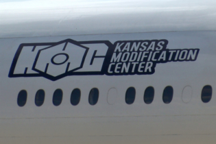 Un fuselage d'avion portant le logo de Kansas Modification Center (KMC), entreprise américaine spécialisée dans la conversion d'avions de passagers en avions cargo.